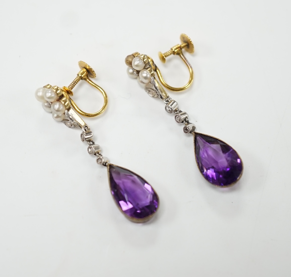 A pair of early to mid 20th century 9ct, amethyst, diamond and seed pearl set drop ear clips, 34mm, gross weight 4.7 grams. Fair to poor condition.